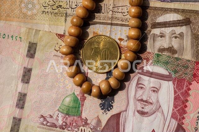 Top view of money, banknote and coin of Saudi Arabia Riyals and prayer beads, in shallow focus