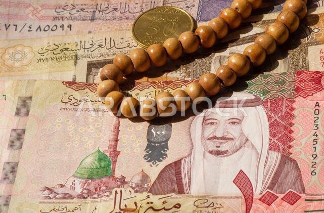 Top view of money, banknote and coin of Saudi Arabia Riyals and prayer beads, in shallow focus