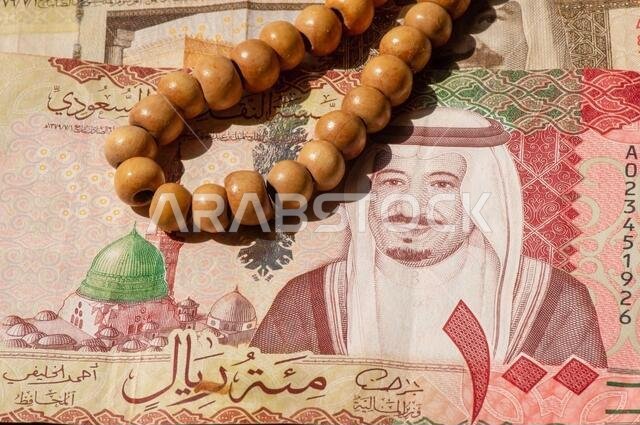 Top view of money, banknote and coin of Saudi Arabia Riyals and prayer beads, in shallow focus