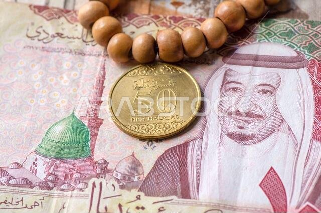 Top view of money, banknote and coin of Saudi Arabia Riyals and prayer beads, in shallow focus