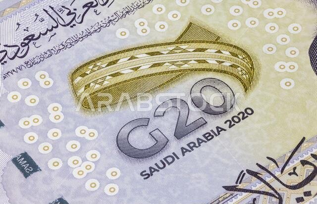 صورة مقرّبة ومفصّلة لـ 20 ريالًا سعوديًا. العملة السعودية المستخدمة في قمة مجموعة العشرين عام 2020. عملة المملكة العربية السعودية. خريطة العالم على الوجه الآخر للورقة.