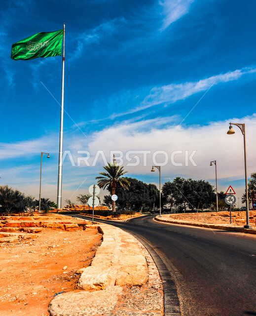 Close-up of the Saudi flag pole flying in the sky, celebrating the Saudi national day, roads and streets, trees and plants, patriotism, Saudi independence day, Saudi national day celebration