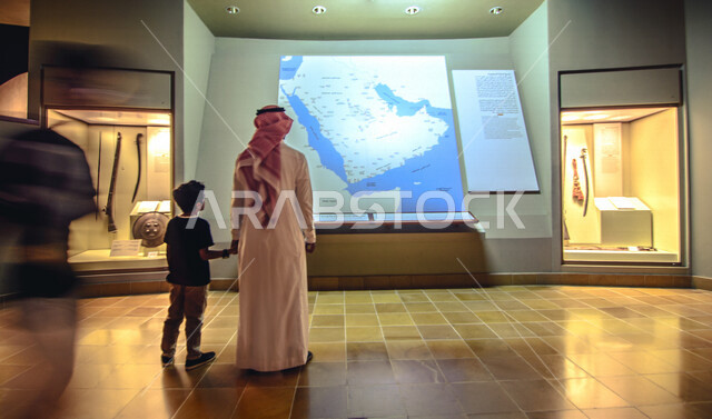 صورة من الخلف لرجل عربي خليجي سعودي وبجانبه ابنه داخل متحف الملك عبد العزيز في الرياض بالمملكة العربية السعودية، معالم السعودية التاريخية، مركز الملك عبد العزيز الثقافي، السياحة في السعودية