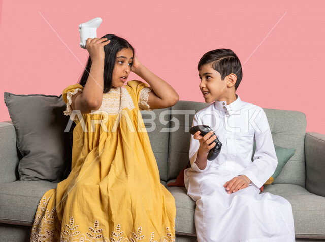 بورتريه لطفلان عربيان خليجيان سعوديان يحملان عصا التحكم، صديقان يستمتعان بلعب العاب الفيديو، اللعب والترفيه، التحدي والمغامرة، مفهوم الفوز والخسارة، تقنيات وألعاب، ايماءات وجه ويدين تدل على الفوز والانتصار، خلفية ملونة