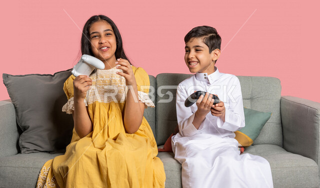 بورتريه لطفلان عربيان خليجيان سعوديان يحملان عصا التحكم، صديقان يستمتعان بلعب العاب الفيديو، اللعب والترفيه، التحدي والمغامرة، مفهوم الفوز والخسارة، تقنيات وألعاب، ايماءات وجه ويدين تدل على الفوز والانتصار، خلفية ملونة