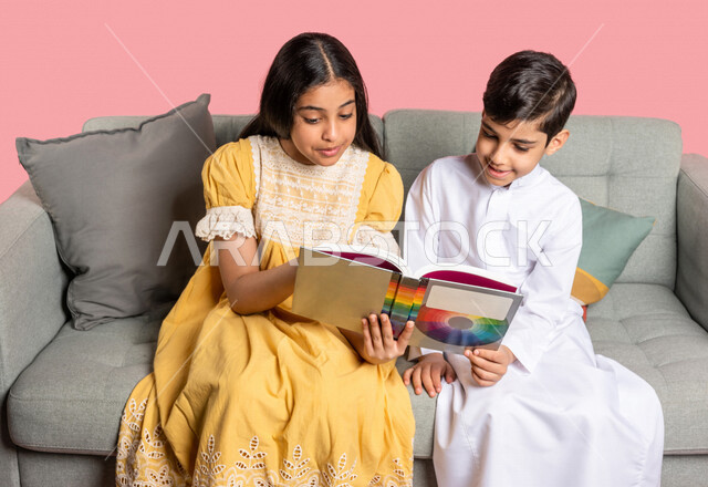بورتريه لطفلان عربيان خليجيان سعوديان يستمتعان بالقراءة، قراءة الكتب، كتاب مدرسي، قصص وروايات، اكتساب المعرفة، تعليم وثقافة، خلفية ملونة