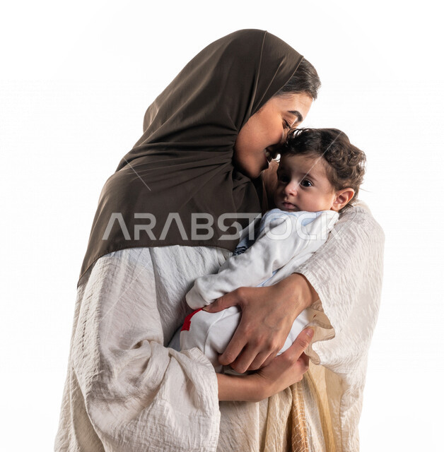 بورتريه لأم عربية خليجية سعودية تحمل طفلها الرضيع بسعادة وحنان، إيماءات تدل الحب والأمان، مفهوم الأمومة والطفولة، حنان الأمهات، رعاية الأم لأطفالها والعناية بهم ، قضاء أوقات جميلة مع الاطفال، الأسرة وتحمل المسؤولية، خلفية بيضاء