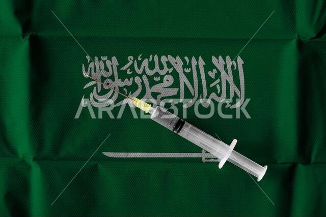 مفهوم الجهود المستمرة التي تبذلها المملكة العربية السعودية لتوصيل وتوزيع لقاح كوفيد-19 مع حقنة جاهزة للاستخدام على العلم السعودي.
