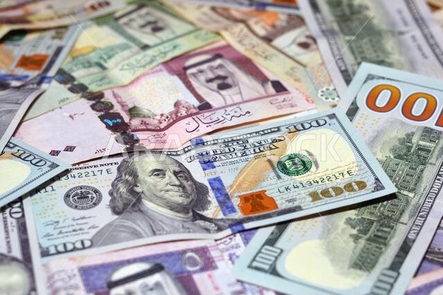 عملة المملكة العربية السعودية مع أوراق نقدية من الدولار الأمريكي. عملة غير واضحة. سعر صرف العملة السعودية مقابل الدولار الأمريكي، 100 دولار، عملات سعودية مختلفة