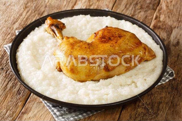 طبق صلي عربي مصنوع من أرز أبيض كريمي مع قطع دجاج، صورة مقربة في طبق على الطاولة. أفقي