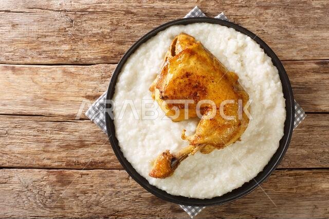 Traditional Arabian dish Saleeg of creamy white rice served with chicken close-up in a plate on the table. horizontal top view from above