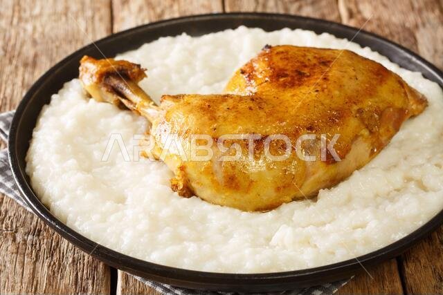 Traditional Arabian dish Saleeg of creamy white rice served with chicken close-up in a plate on the table. horizontal