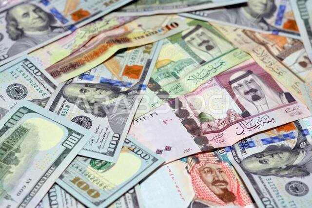 عملة المملكة العربية السعودية مع أوراق نقدية من الدولار الأمريكي. عملة غير واضحة. سعر صرف العملة السعودية مقابل الدولار الأمريكي، 100 دولار، عملات سعودية مختلفة