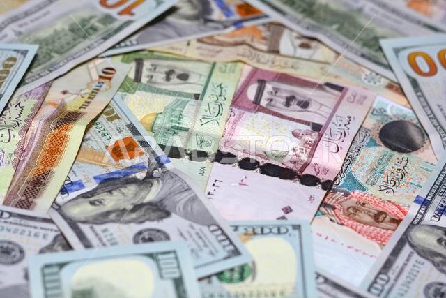 عملة المملكة العربية السعودية مع أوراق نقدية من الدولار الأمريكي. عملة غير واضحة. سعر صرف العملة السعودية مقابل الدولار الأمريكي، 100 دولار، عملات سعودية مختلفة