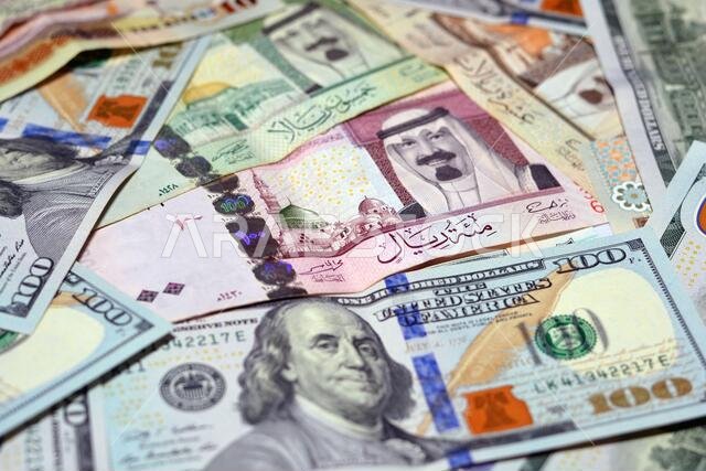 عملة المملكة العربية السعودية مع أوراق نقدية من الدولار الأمريكي. عملة غير واضحة. سعر صرف العملة السعودية مقابل الدولار الأمريكي، 100 دولار، عملات سعودية مختلفة