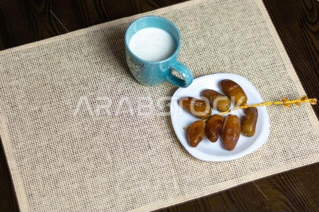 صورة علوية لتمور جزائرية على طبق أبيض مع كوب من الحليب، مفهوم رمضان، مساحة للنص