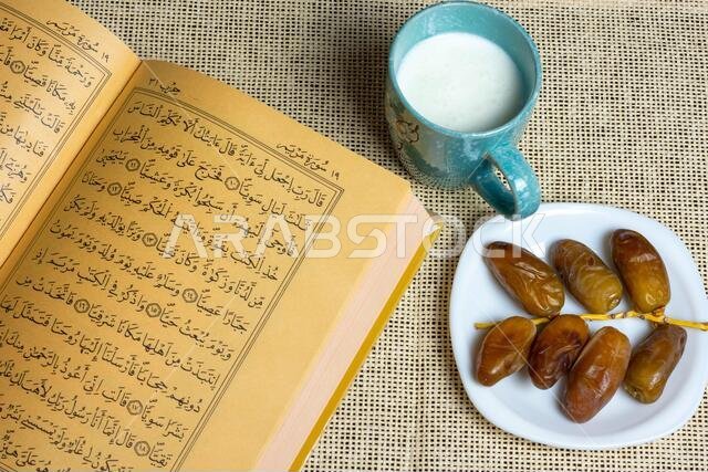 منظر علوي للقرآن الكريم وتمور جزائرية مع كوب من الحليب، مفهوم رمضان