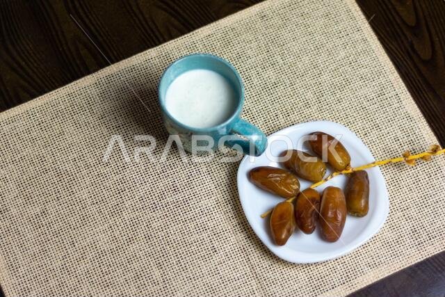 صورة علوية لتمور جزائرية على طبق أبيض مع كوب من الحليب، مفهوم رمضان، مساحة للنص
