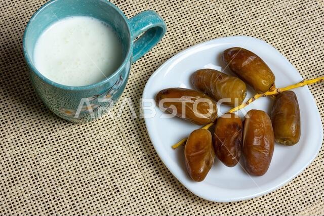Top view of Algerian dates on a white plate with a mug of milk, Ramadan concept, space for text