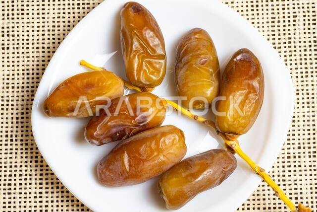 صورة علوية لتمور جزائرية ملكية على طبق أبيض، مفهوم رمضان، مساحة للنص