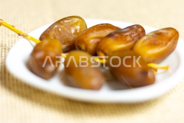 صورة مقرّبة لتمور جزائرية ملكية على طبق أبيض، مفهوم رمضان