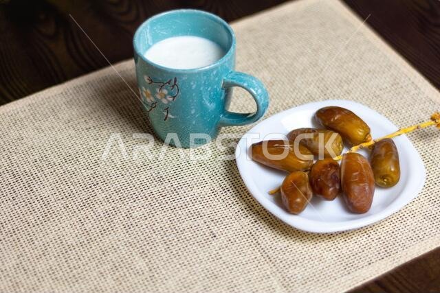 صورة علوية لتمور جزائرية على طبق أبيض مع كوب من الحليب، مفهوم رمضان، مساحة للنص
