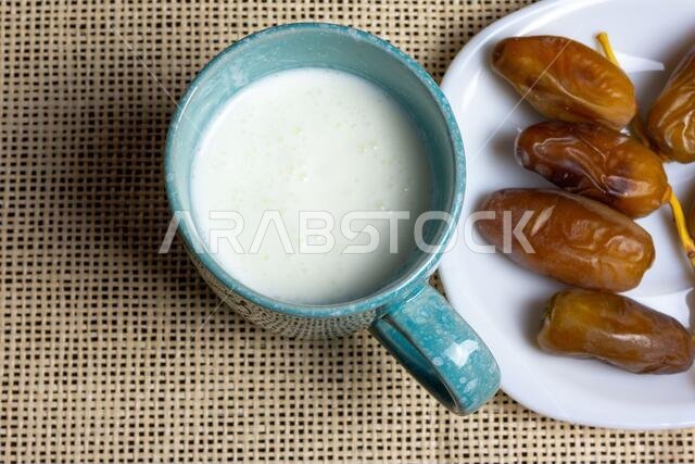 Top view of Algerian dates on a white plate with a mug of milk, Ramadan concept, space for text