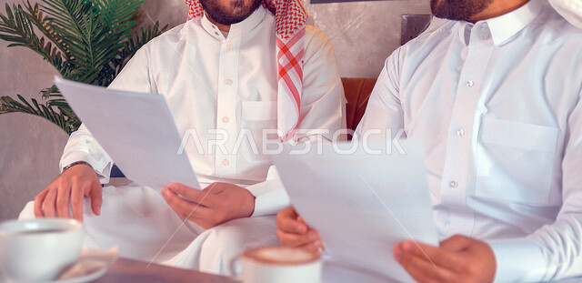 صورة مقربة لرجلان عربيان خليجيان سعوديان يقومان بمتابعة ومناقشة الأعمال والمشاريع، مهن وأعمال تجارية، بيئة عمل، زملاء عمل، تطوير المشاريع، عقد صفقات تجارية، دراسة المشاريع الجديدة، متابعة ومناقشة إستراتيجيات وأهداف الشركة