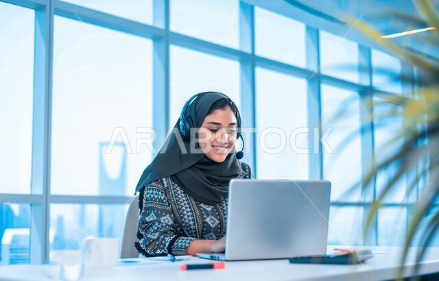 مرأة عربية خليجية سعودية ترتدي سماعة الرأس الصوتية، تعمل في مجال خدمة العملاء في شركة، استعلامات واستفسارات، الاجابه على اسئلة العملاء، اجراء اتصال من خلال جهاز الحاسوب المحمول، عقد اجتماع عمل عبر الانترنت، متابعة وتطوير العمل، الدعم الفني، جلسة عمل