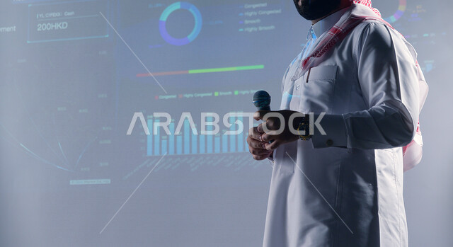 رجل عربي سعودي خليجي في مؤتمر إقتصادي، خلفية رسوم بيانية إحصائية للبورصة المالية، تطوير الشركات والمشاريع الاقتصادية، تحليل البيانات المالية، متابعة الأسهم، الإستثمار المالي، رؤية مستقبلية، شرح الرسم البياني لسوق الأوراق المالية، رؤية 2030