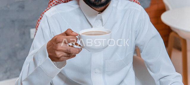 صورة مقربة لرجل عربي خليجي سعودي يجلس في المقهى ، يشرب القهوة الساخنة ، مطاعم وكافيهات السعودية ، متجر القهوة السعودي