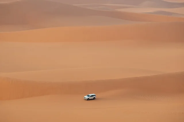 White SUV Driving Through Al-Nafud Desert Dunes