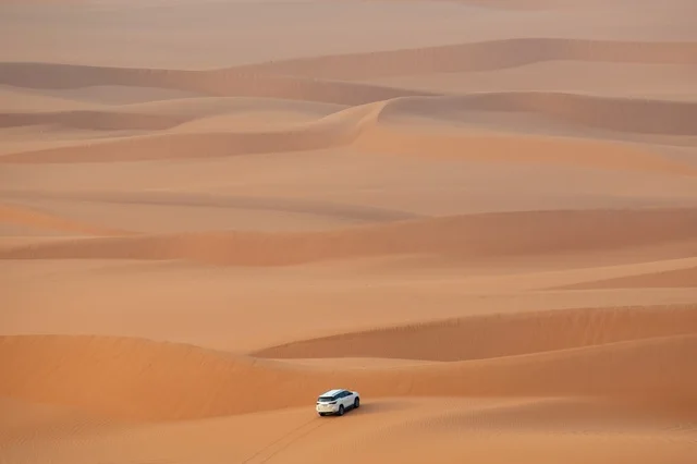 White SUV Driving Through Al-Nafud Desert Dunes