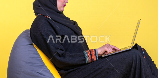 بورتريه بصورة مقربة لمرأة خليجية سعودية، إستخدام جهاز الحاسوب المحمول، التعليم والعمل عن بعد، إستخدام أجهزة تقنية حديثة، التسويق الإلكتروني، تصفح الإنترنت، مهن ووظائف، التسليه والترفيه، مشاهدة الأفلام عبر اللابتوب، جلسة عمل، خلفية صفراء
