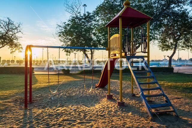 أطفال يلعبون في متنزه الملك فهد بالدمام في المملكة العربية السعودية مع خلفية شروق الشمس.