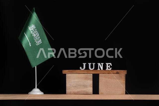 Wooden calendar of June with Saudi Arabia flag on black background. Dates of Saudi Arabia in June.