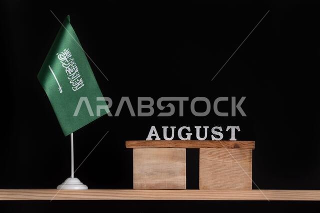 Wooden calendar of August with table Saudi Arabia flag on black background. Holidays of Saudi Arabia in August.