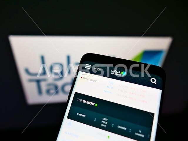 Mobile phone with business web page of Saudi Arabian stock exchange Tadawul on screen in front of company logo. Focus on top-left of phone display.