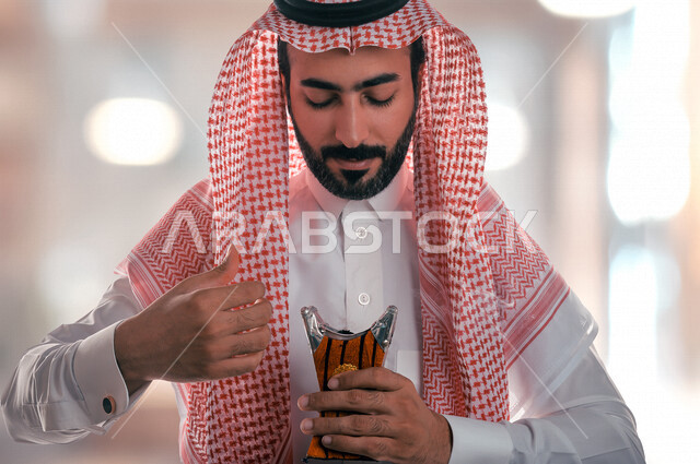 رجل عربي خليجي سعودي يحمل بيده المبخرة، حامل البخور، استخدام خشب العود في المناسبات الاجتماعية والمناسبات الدينية، اصالة العادات والتقاليد في المملكة العربية السعودية ، التطيب والتعطر