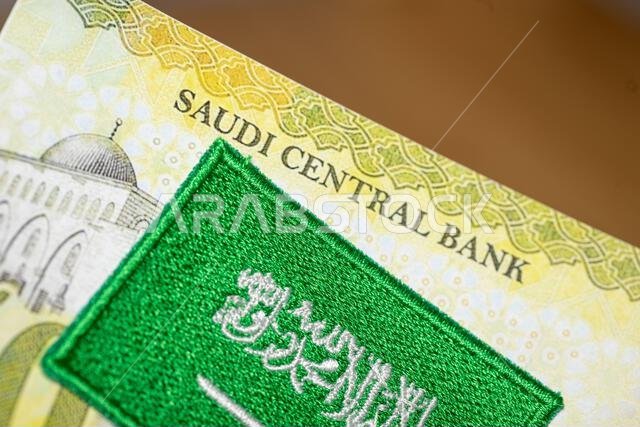 Embroidered Saudi Arabia flag and banknote with the words Saudi Central Bank, Financial business concept, Saudi Arabia money
