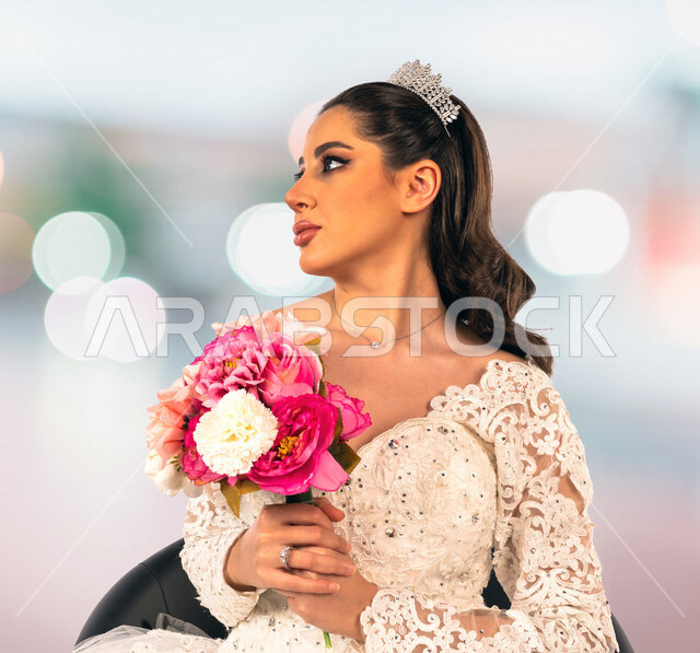 عروسة عربية خليجية سعودية جميلة ترتدي بدلة الزفاف البيضاء وتحمل بيدها باقة ورد جميلة، جلسة تصوير، بإيماءات وجه ويدين مختلفة، اطلالة لعروسة في يوم زفافها، ليلة العمر، مناسبات وأفراح