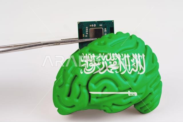 On a white background, a model of the brain with a picture of a flag - Saudi Arabia, a microcircuit, a processor, is implanted into it. Close-up