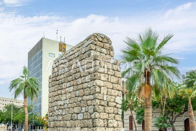 أطلال حجرية لمبانٍ عربية قديمة تتخللها أشجار النخيل في شارع البلد، جدة، المملكة العربية السعودية