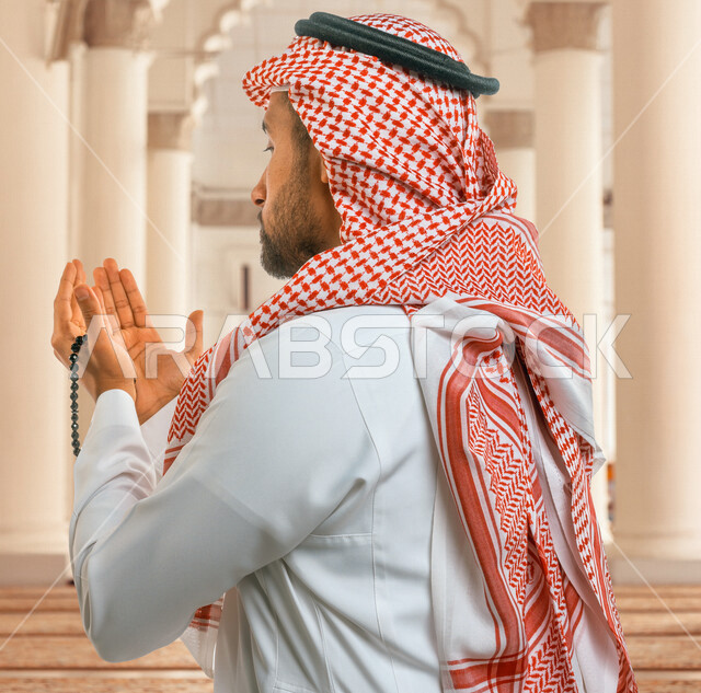 صورة مقربة لرجل عربي خليجي سعودي يرفع يديه لاعلى، الدعاء والتضرع الى الله اثناء الصلاة، العبادة والتقرب الى الله، الصلاة والتسبيح، أذكار وأدعية، خلفية داخل المسجد، إسلاميات وعبادة