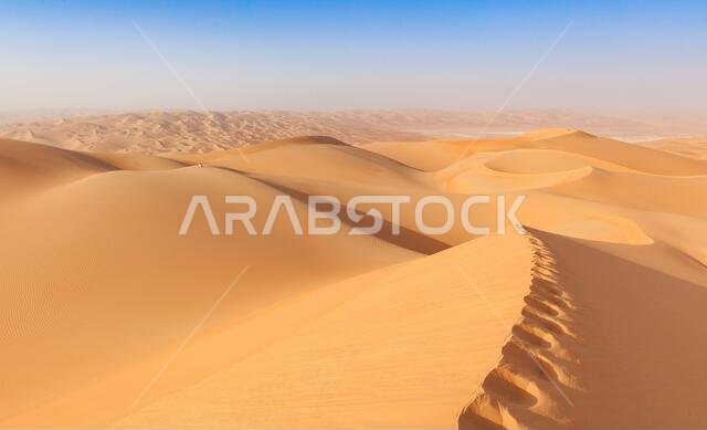 رجل يرتدي الزي العماني التقليدي يجلس على كثيب رملي في الصحراء العربية
