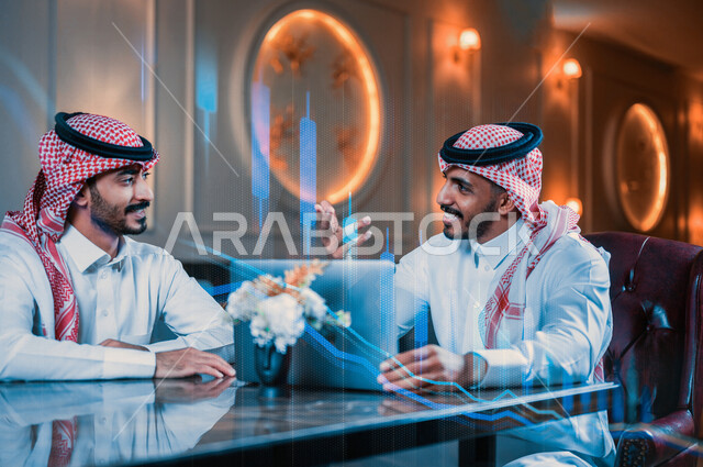 رجلان اعمال عربيان خليجيان سعوديان يجتمعان في احد المقاهي، حوار ونقاش عمل خارج الشركة، استخدام الحاسوب المحمول في انجاز مهام العمل، إدارة الأعمال عن بعد، زملاء عمل، مقاهي في المملكه العربيه السعوديه