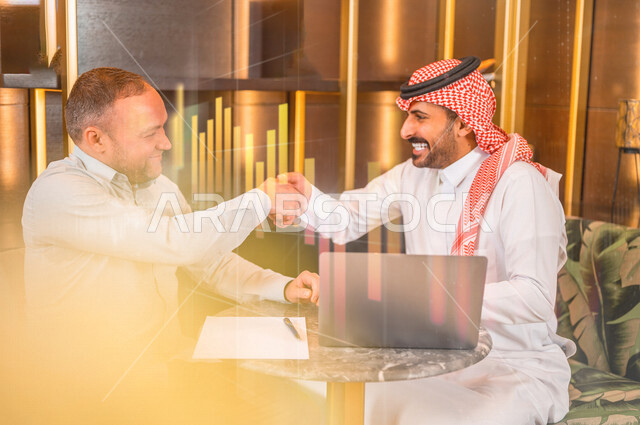 رجلان أعمال عربيان خليجيان سعوديان يتصافحان بسعادة، شركاء عمل يجتمعان في أحد الفنادق الخليجية، إتفاق عمل جديد، الشراكة على الأعمال والمشاريع التجارية، صفقات عمل وتعاون بين الشركات  
