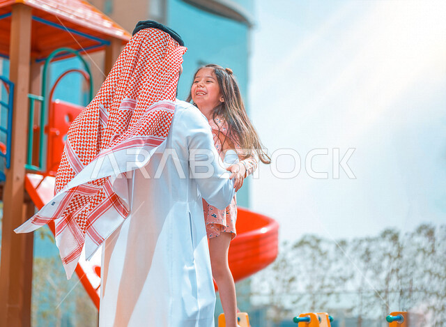 رجل عربي خليجي سعودي مستمتع بقضاء وقت ممتع مع ابنته في احد الحدائق بالمملكة العربية السعودية، التسلية والترفيه، اجواء صيفية ممتعة، قضاء وقت عائلي ممتع، عطلة صيفية سعيدة