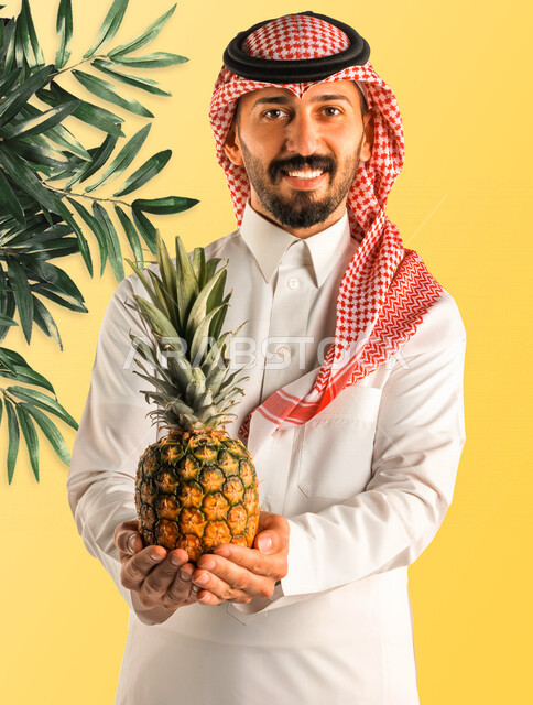 بورتريه لرجل عربي خليجي سعودي يحمل بيده فاكهة الأناناس، فواكه صحية، تناول وجبة طعام صحيه خفيفه، وجبات الدايت، الصحة والرشاقة، إيماءات وجه مبتسمة، خلفية صفراء