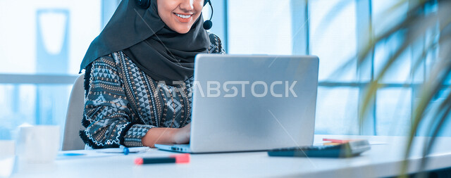إمراه عربيه سعوديه خليجيه ترتدي سماعة الرأس,  العمل في خدمة العملاء في شركه, استعلامات واستفسارات, الاجابه على اسئلة العملاء, اجراء اتصال فيديو من خلال الحاسوب , عقد اجتماع عمل عبر الانترنت, متابعة وتطوير العمل, خلفيات هولوجراميه ثلاثية الابعاد